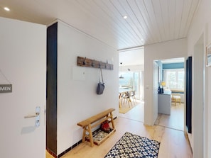 A hallway with a wooden bench, a coat rack, and a patterned rug. - Apartment  by Interhome (Valbella)