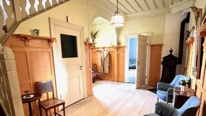 A room with wooden flooring, a blue armchair, a small table, and a door leading to another room. - Summer House Sweden in Rättvik for 9 people by Interhome (Rättvik)