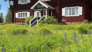 A two-story wooden house with a porch and a staircase leading to the entrance. - Summer House Sweden in Rättvik for 9 people by Interhome (Rättvik)