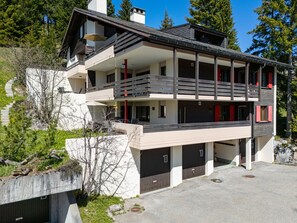 Ein mehrgeschossiges Gebäude mit Balkon, Garage und Auffahrt.
