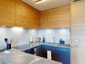 A modern kitchen with wooden cabinets, a granite countertop, and stainless steel appliances.