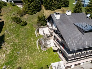 A modern two-story house with a sloped roof, a visible satellite dish, and a paved patio area.