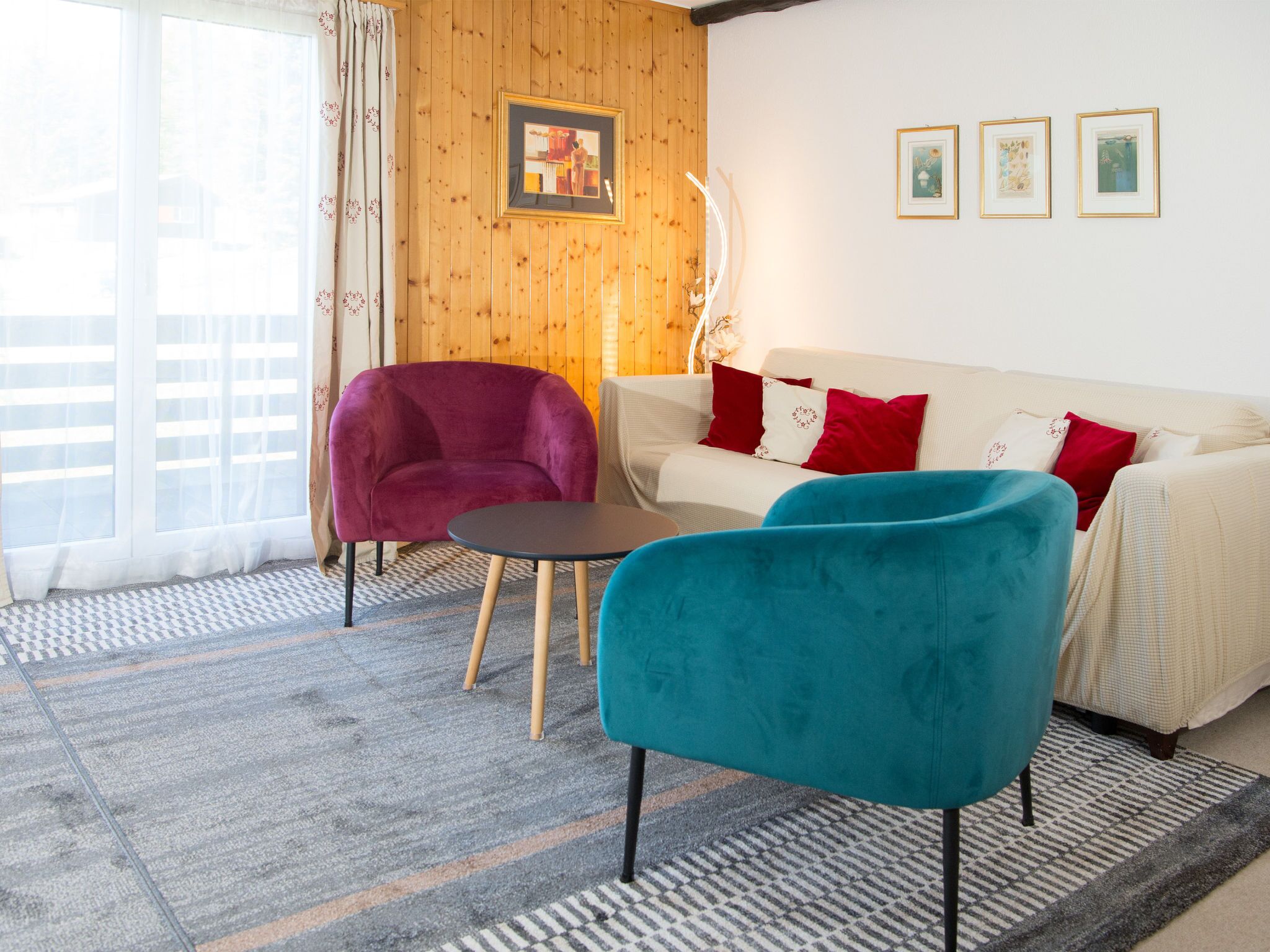 Una sala de estar con un sofá, dos sillones, una mesita y un tapete estampado.