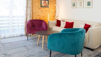 Una sala de estar con un sofá, dos sillones, una mesita y un tapete estampado.