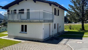 A two-story building with a balcony, a small attached garage, and a paved driveway. - 1505 Chesa Katja by Interhome (Valbella)