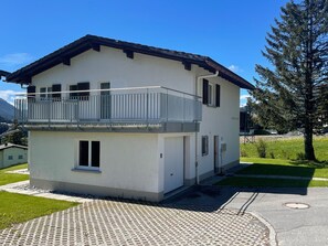 A two-story building with a balcony, a small attached garage, and a paved driveway. - 1505 Chesa Katja by Interhome (Valbella)