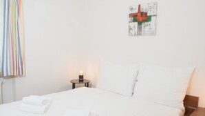 A hotel room with a neatly made bed, a bedside table with a lamp, and a painting on the wall. - 1505 Chesa Katja by Interhome (Valbella)