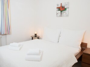 A hotel room with a neatly made bed, a bedside table with a lamp, and a painting on the wall. - 1505 Chesa Katja by Interhome (Valbella)