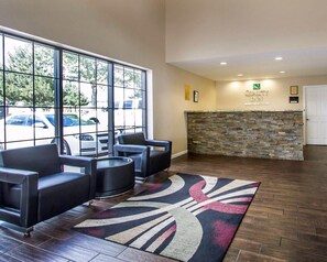 A reception area with a stone wall, a reception desk, and a seating area with chairs and a table. - Quality Inn Flagstaff East I-40 (Flagstaff)
