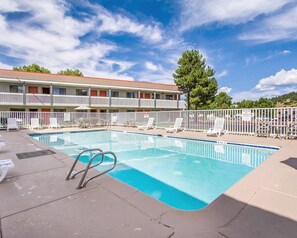 A swimming pool with lounge chairs and a building with balconies in the background. - Quality Inn Flagstaff East I-40 (Flagstaff)