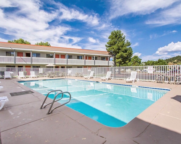 A swimming pool with lounge chairs and a building with balconies in the background. - Quality Inn Flagstaff East I-40 (Flagstaff)