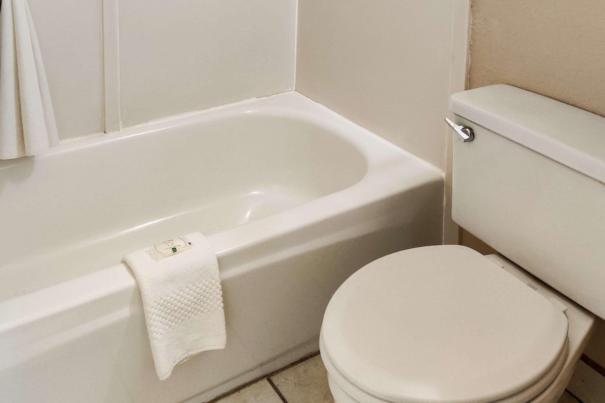 Un baño con una bañera blanca, inodoro y una toalla colgada de la bañera.
