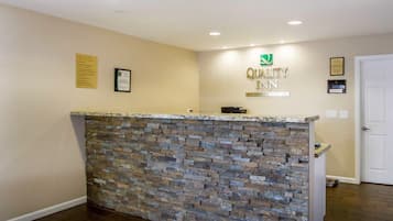 Uma receção com fachada de pedra, um letreiro a indicar 'Quality Inn by Choice Hotels' e uma porta à direita.