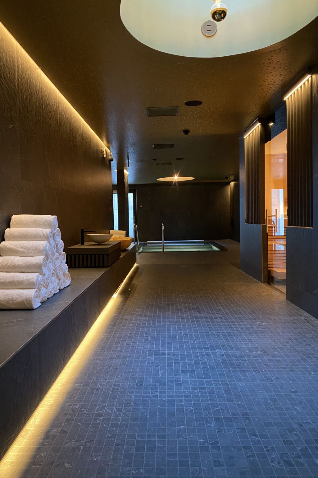 A spa area with a tiled floor, a towel rack, and a reception desk.
