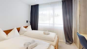 Une chambre d’hôtel avec deux lits, un bureau et une vue sur l’extérieur.