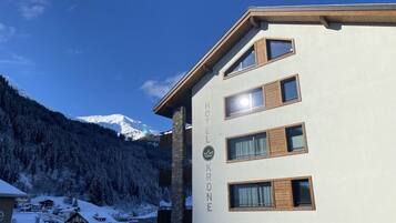 A hotel building with multiple windows and a mountain in the background.