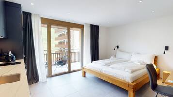 Habitación de hotel moderna con una cama grande, un escritorio y un balcón con vistas al edificio.