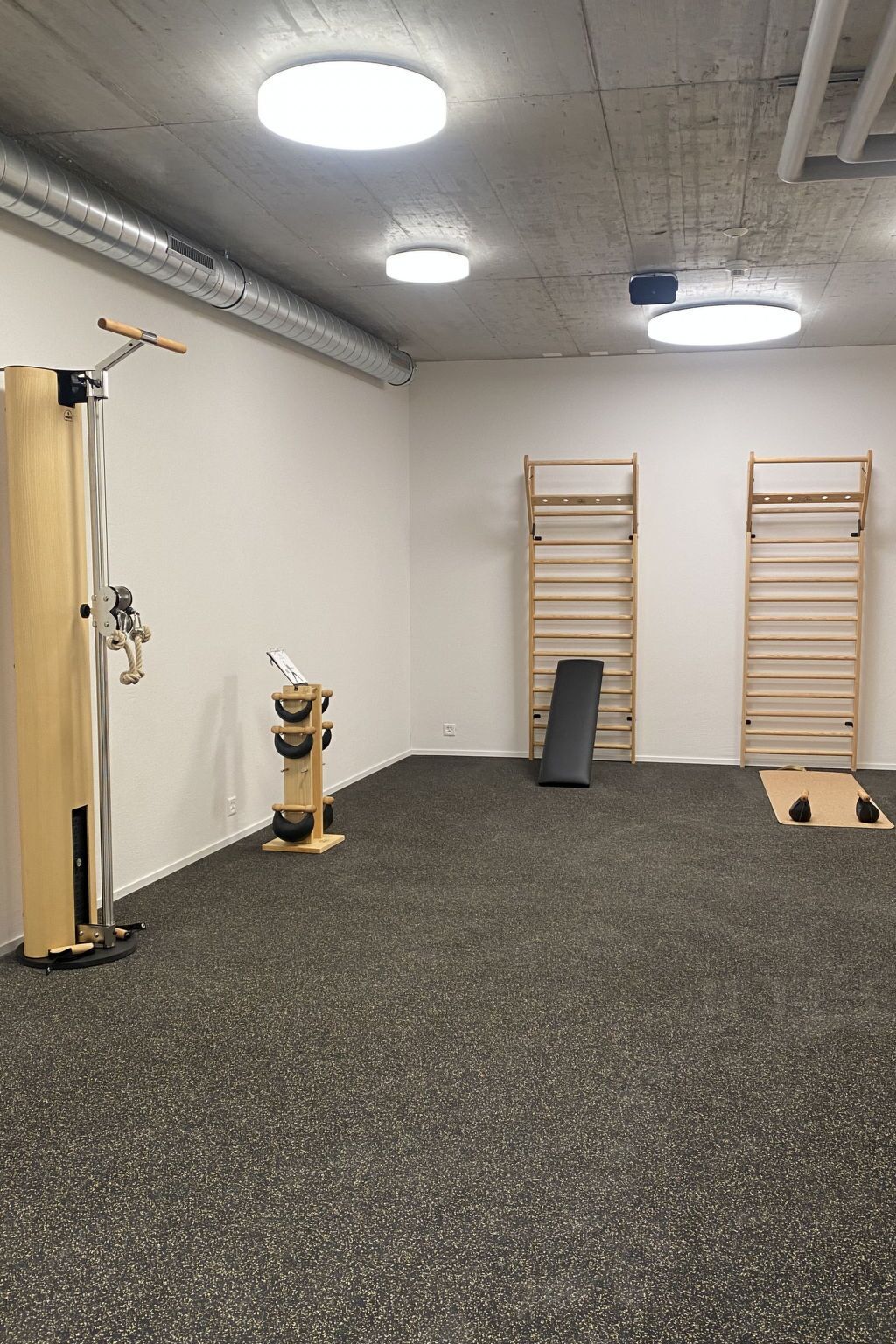 A gym with a pull-up bar, a wooden rack, and a black mat.
