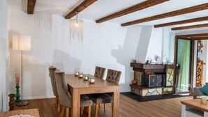 A dining area with a wooden table and chairs, a hanging light fixture, and a stone fireplace. - 1507 Davos Lai Valbella by Interhome (Valbella)