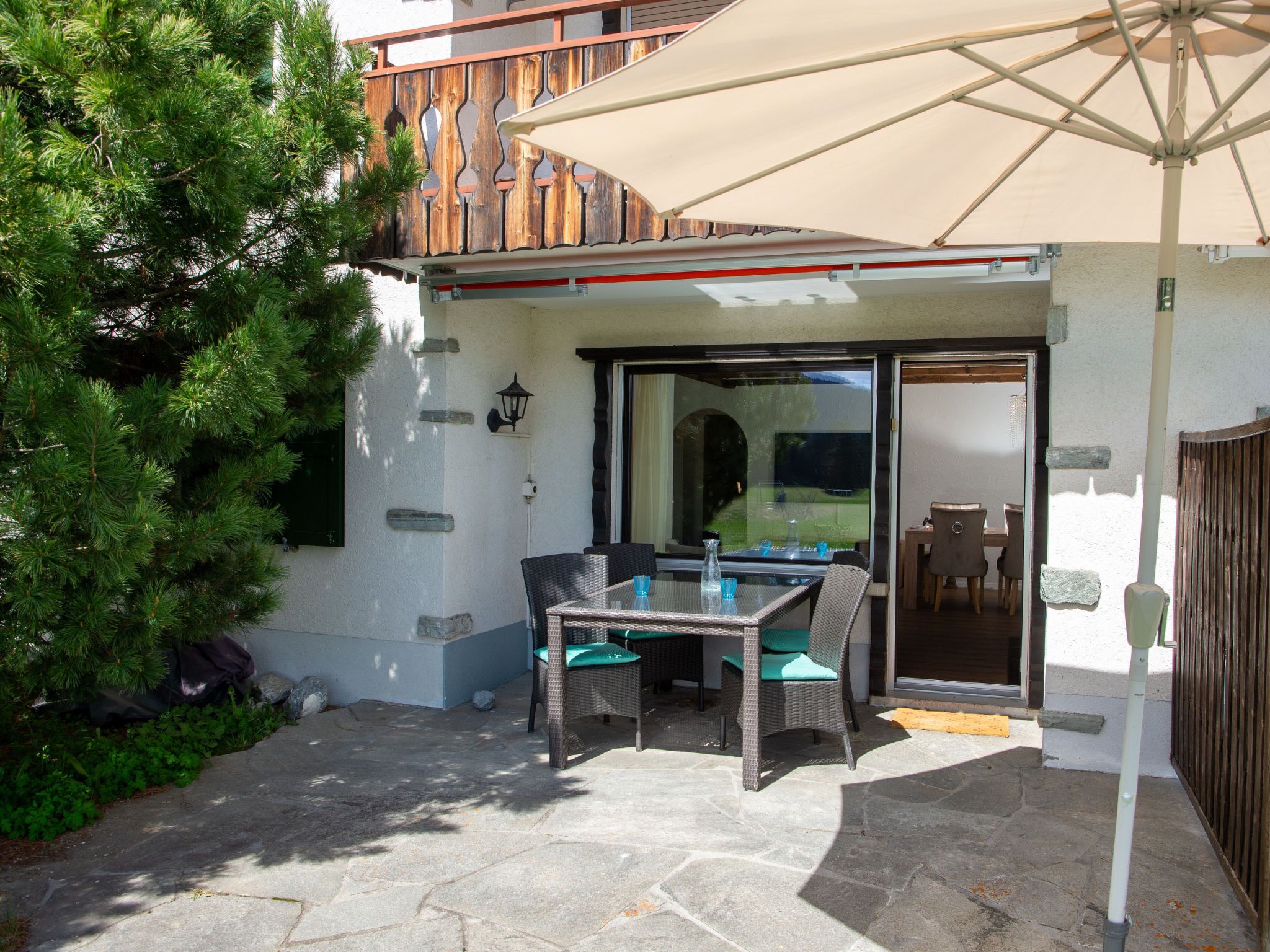 Une terrasse extérieure avec une table et des chaises, une clôture en bois et un arbre en pot.