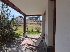 A covered outdoor area with a bench, a wooden post, and a view of a building in the background. - 1604 Schweizerhof 405 by Interhome (Lenzerheide)