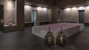 Un baño amplio y moderno con un lavamanos central grande, bancos y faroles decorativos.