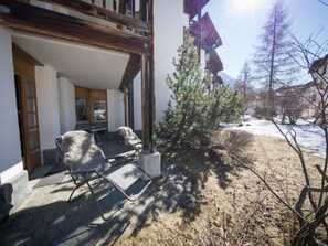 Ein Gebäude mit überdachter Veranda, Gartenmöbeln und einem kleinen Baum.