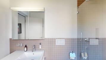 Une salle de bain moderne avec un grand lavabo blanc, un miroir et un espace douche.