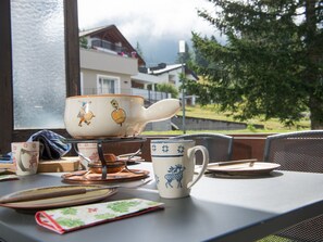 A table set with a teapot, cups, and plates, with a view of houses and trees outside. - 1611 Pianura Crapera by Interhome (Lenzerheide)