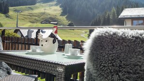 A balcony with a view of a mountainous landscape, a white teapot, two cups, and a furry object in the foreground. - 1401 Heimberg by Interhome (Parpan)