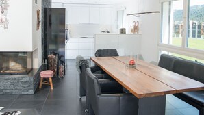 A modern kitchen with white cabinets, a stone accent wall, and a built-in fireplace. - 1401 Heimberg by Interhome (Parpan)