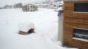 A snowy residential area with houses and a wooden building. - 1401 Heimberg by Interhome (Parpan)