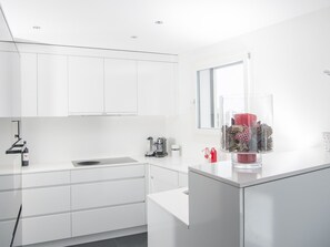 A modern kitchen with white cabinetry, a built-in sink, and a window above the counter. - 1401 Heimberg by Interhome (Parpan)