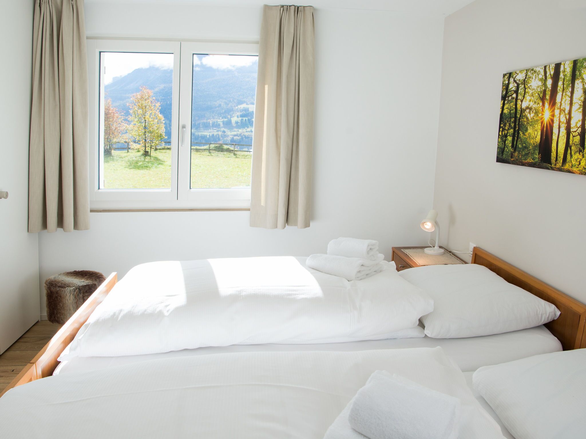 Ein Hotelzimmer mit Bett, Nachttisch, Lampe und einem Fenster mit Vorhängen.
