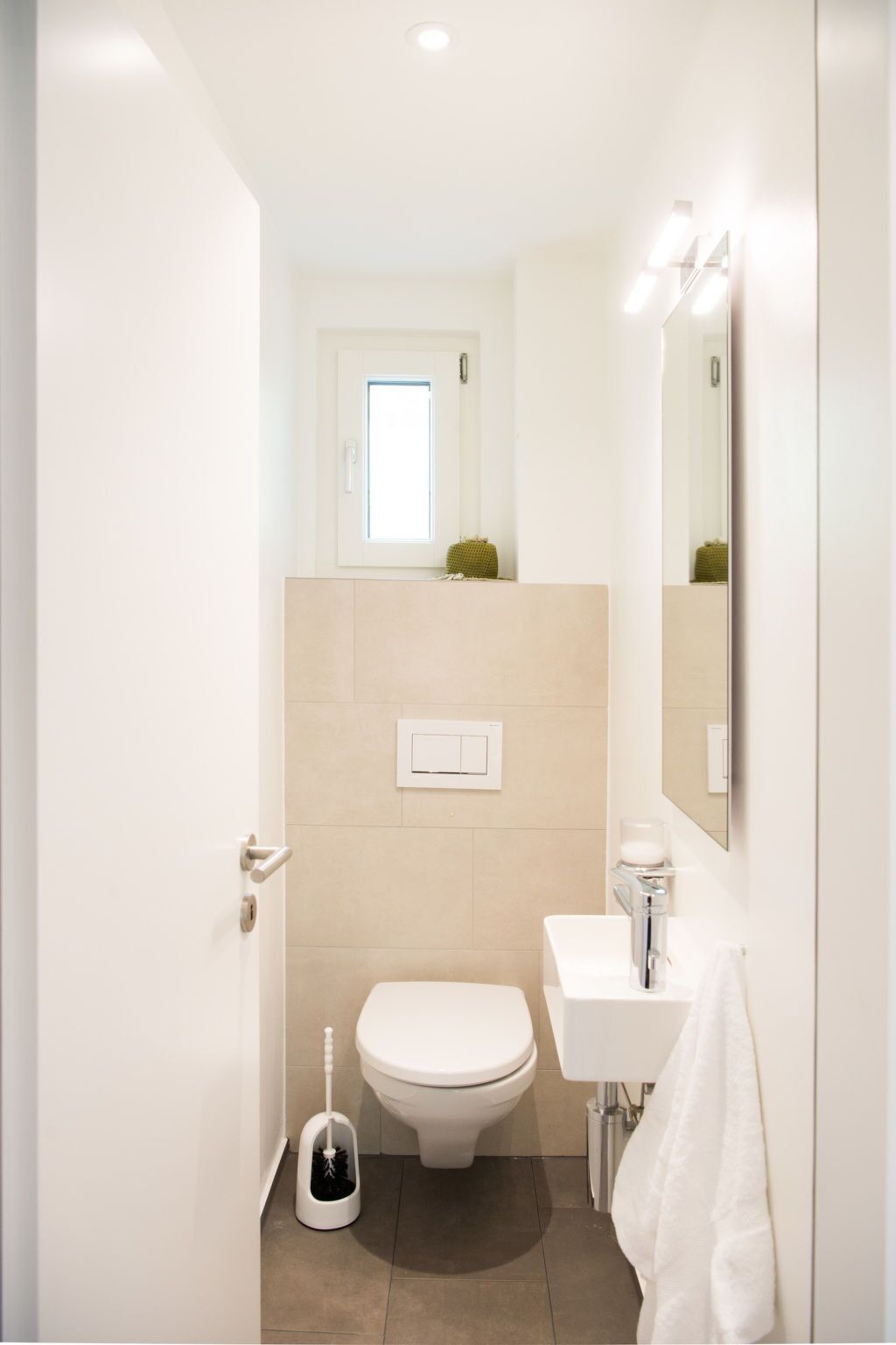 A compact bathroom with a toilet, bidet, sink, and a mirror.