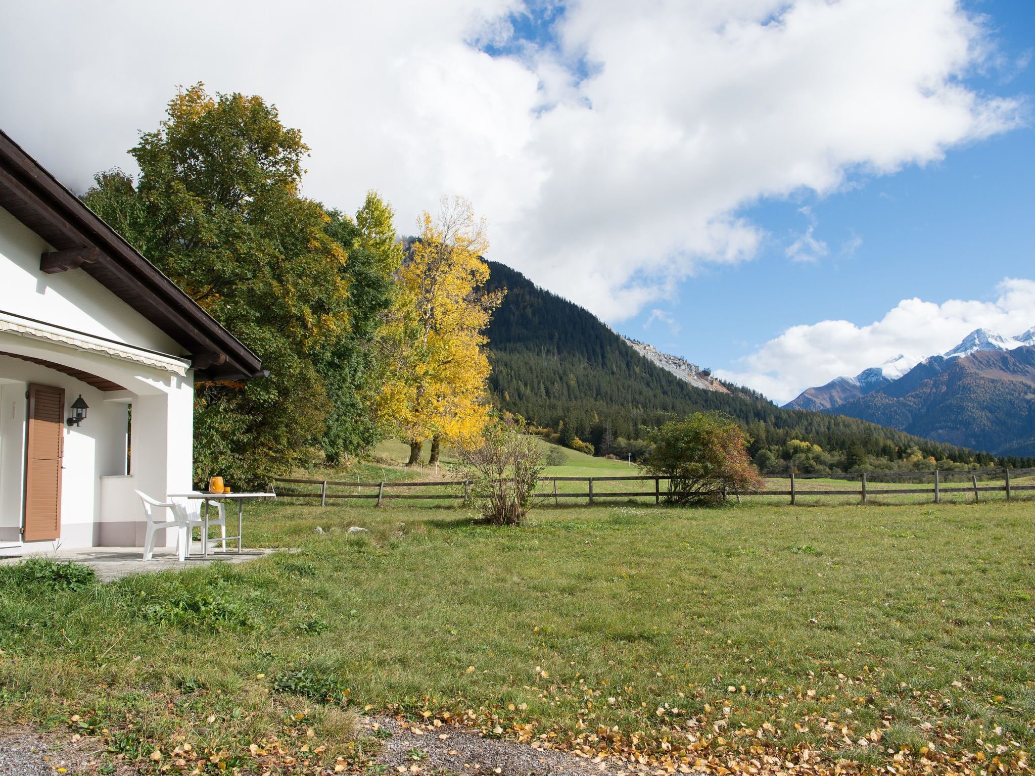 Ein Gebäude mit Veranda, Tisch und Stühlen.