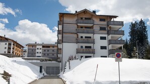 Un edificio de varios pisos con balcones, una entrada cubierta de nieve y un cartel de 'no estacionamiento'.
