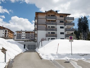 Un edificio de varios pisos con balcones, una entrada cubierta de nieve y un cartel de 'no estacionamiento'.