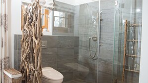 A modern bathroom with a glass shower enclosure, a toilet, and a decorative wooden structure. - 1605 Scalottas by Interhome (Lenzerheide)