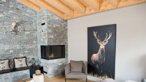 Una sala acogedora con chimenea de piedra, un cuadro de ciervo grande y muebles modernos.