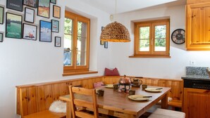 Uma mesa de jantar de madeira com cadeiras, um banco e um lustre.