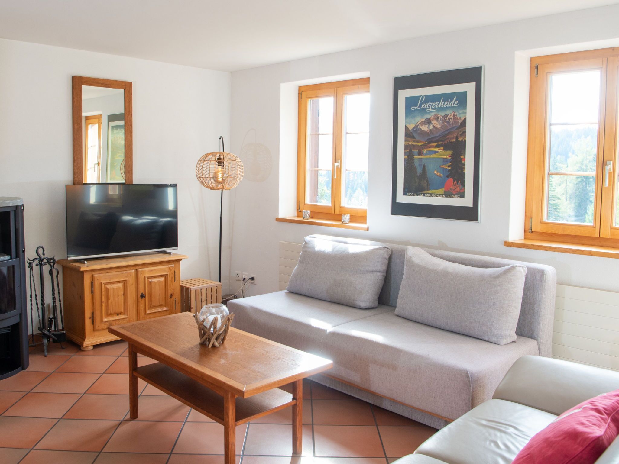 Ein Wohnzimmer mit einer Couch, einem Holztisch, einem Fernseher und einem gerahmten Bild an der Wand.