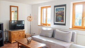Uma sala de estar com um sofá, uma mesa de madeira, uma televisão e um quadro na parede.