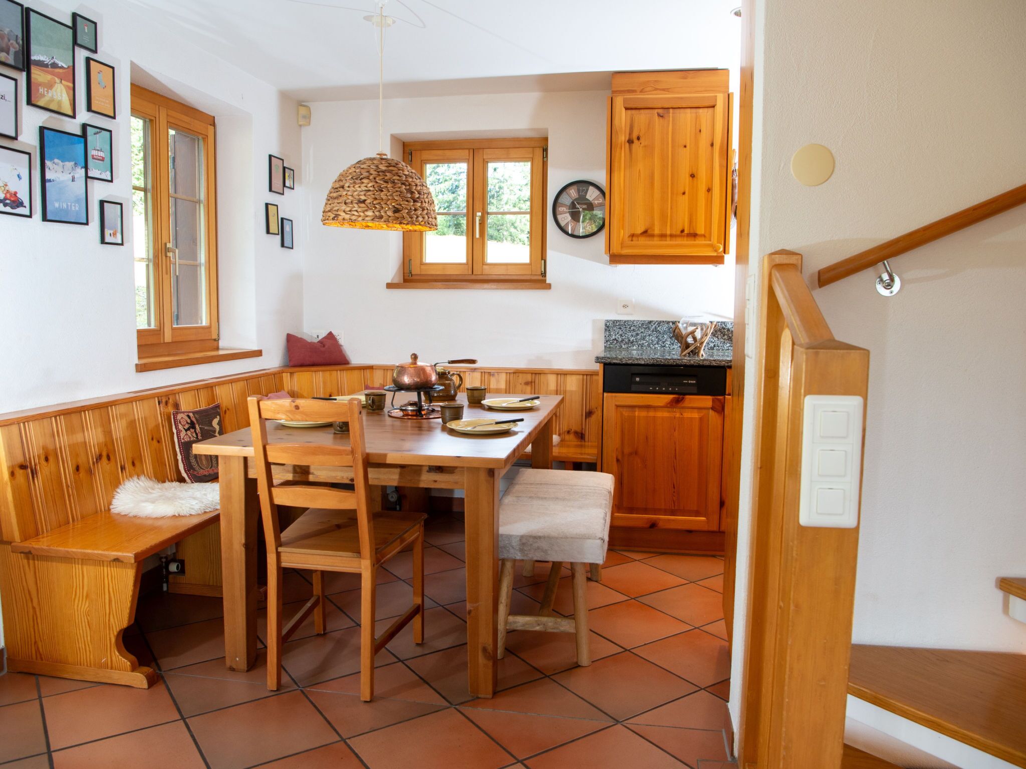 Une cuisine chaleureuse avec des meubles en bois, une table à manger avec des chaises et un luminaire suspendu.
