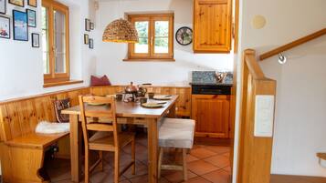 Une cuisine chaleureuse avec des meubles en bois, une table à manger avec des chaises et un luminaire suspendu.