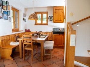 Una cocina acogedora con armarios de madera, una mesa de comedor con sillas y una lámpara colgante.