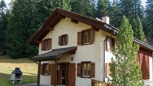 Uma casa de dois andares com telhado inclinado, persianas de madeira e chaminé.