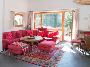 Ein gemütliches Wohnzimmer mit einem roten Sofagarnitur, einem Holztisch und einem gemusterten Teppich.