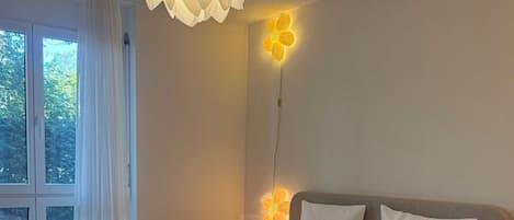 Ein modernes Schlafzimmer mit einem großen Bett, einem roten Nachttisch und einer außergewöhnlichen Deckenleuchte.