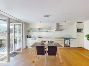 A modern kitchen with a dining area, large windows, and a view of the outside.